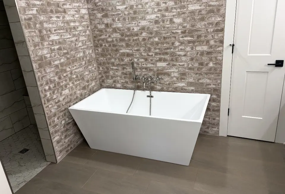Freestanding tub against a stone accent wall in a finished bathroom